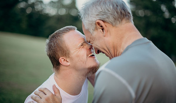 adoptive father and his son with special needs touch foreheads and smile