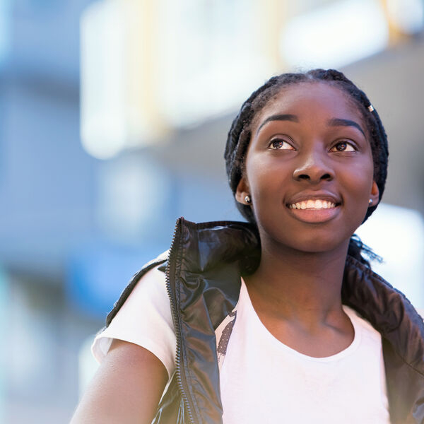 Black teenage refugee girl looks hopefully into the sky