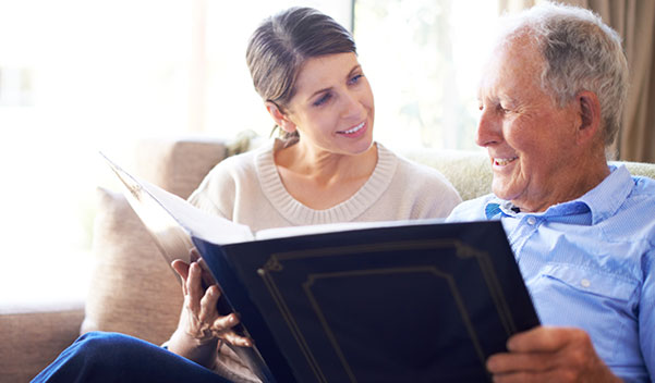 adult adoptee flips through a photo album with her elderly birth father