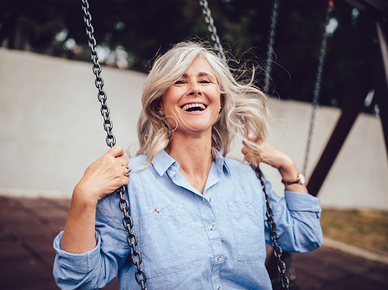 elderly white woman laughs while swinging
