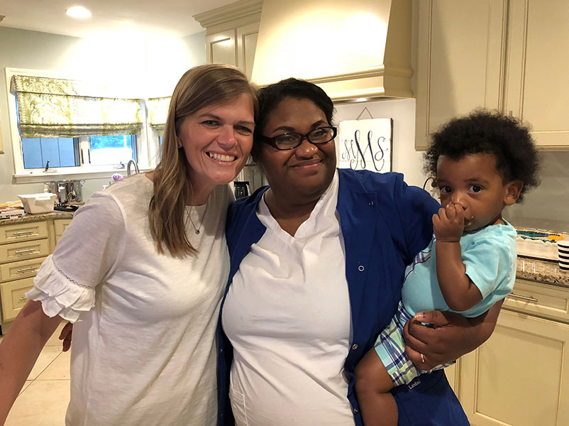 african american mother holds her son while standing with their host parent