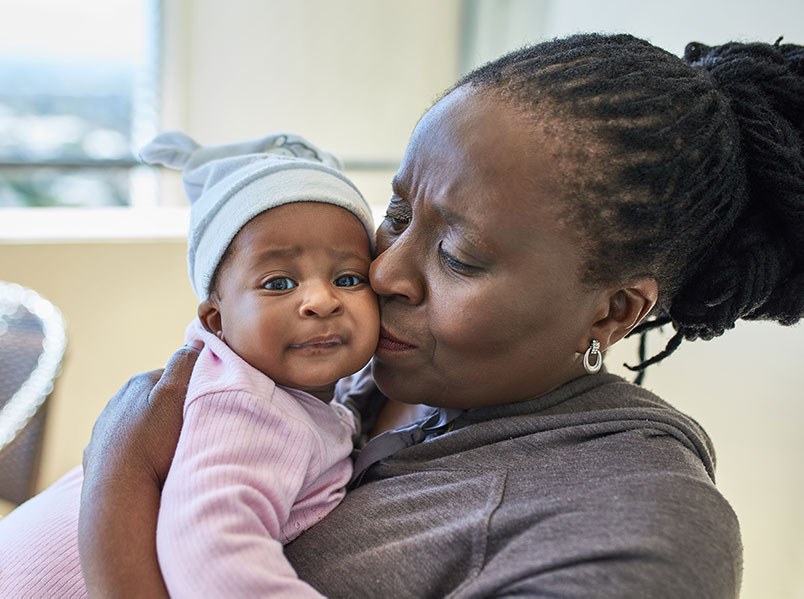 african american grandmother hugs her granddaughter who she has adopted from foster care