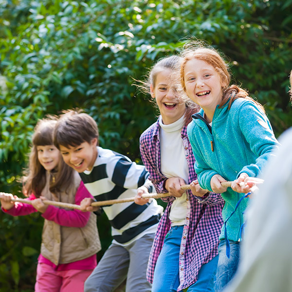 Diverse kids play tug-of-war outside