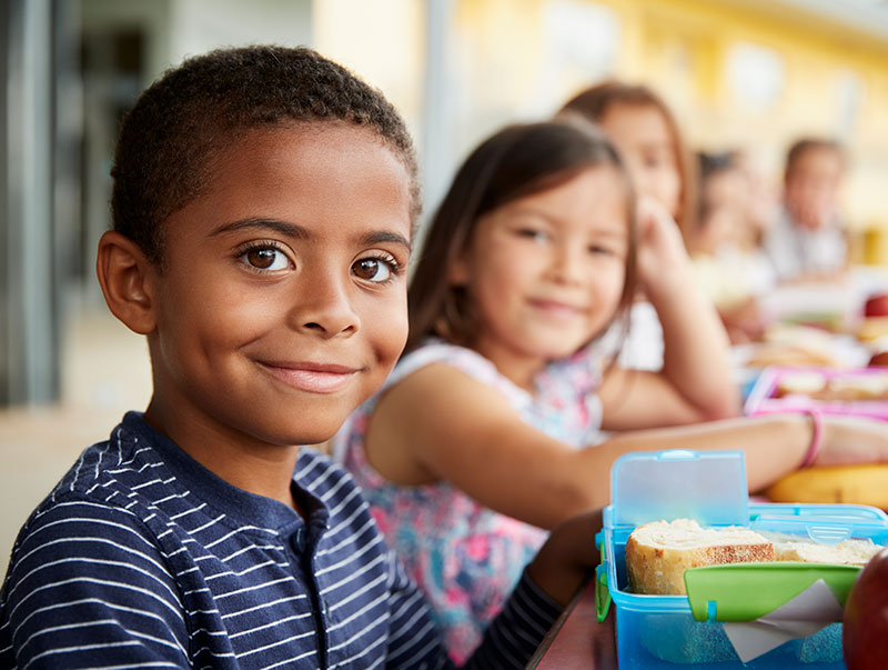 diverse group of schoolchildren eat their lunch