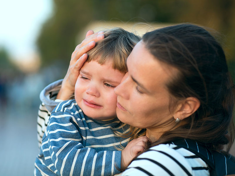 foster mother holds young boy who is crying
